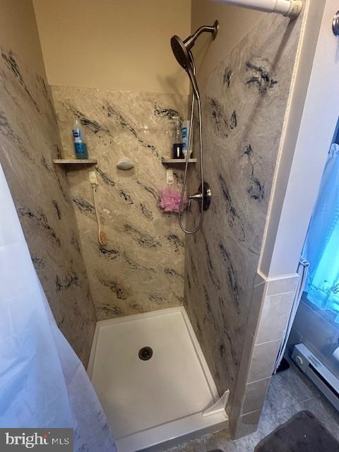 bathroom with a stall shower and a baseboard heating unit