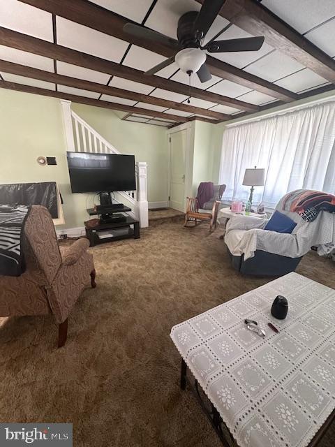 carpeted living area featuring ceiling fan and beam ceiling