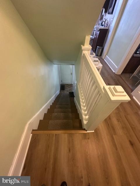 staircase with baseboards and wood finished floors