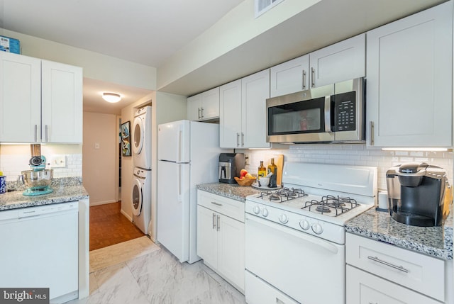 kitchen with white appliances, white cabinetry, backsplash, and stacked washing maching and dryer