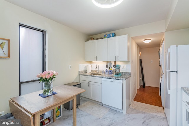 kitchen with marble finish floor, white appliances, a sink, and light stone counters