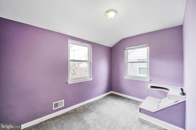 carpeted spare room featuring visible vents, baseboards, and vaulted ceiling