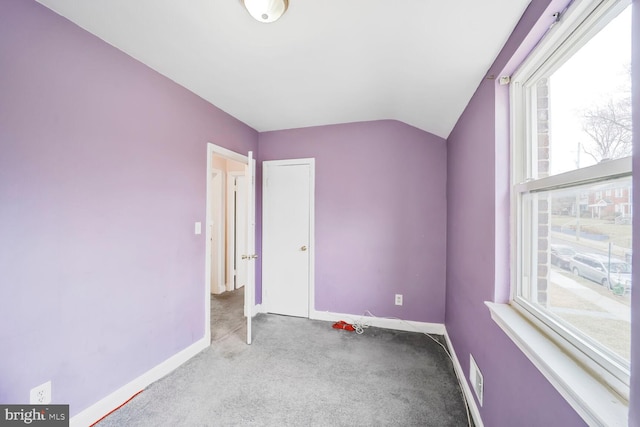 unfurnished bedroom with vaulted ceiling, multiple windows, carpet, and baseboards