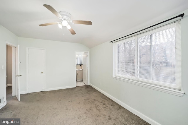 unfurnished bedroom featuring ceiling fan, baseboards, vaulted ceiling, carpet floors, and ensuite bath