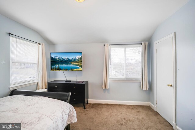 carpeted bedroom with vaulted ceiling and baseboards