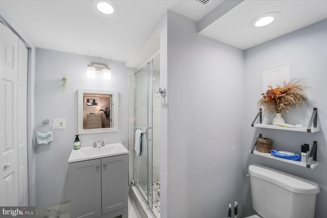 bathroom with vanity, a shower stall, and toilet