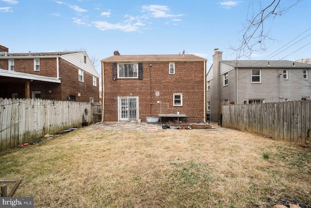 rear view of house featuring a patio, brick siding, a fenced backyard, and a lawn