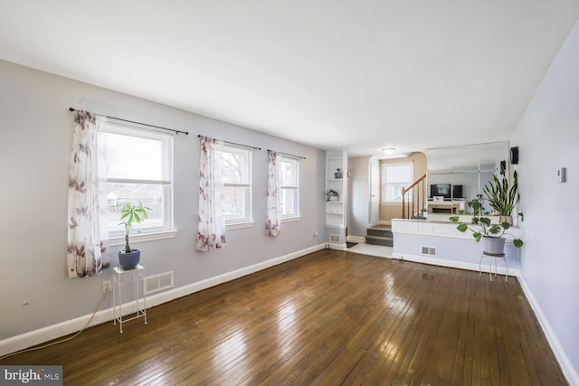 unfurnished living room featuring visible vents, hardwood / wood-style floors, and stairway