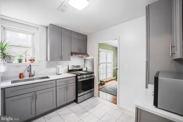 kitchen featuring gray cabinetry, stainless steel gas range, and a sink