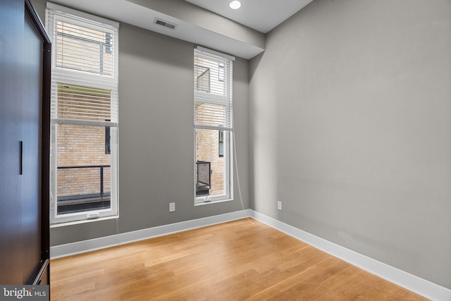 unfurnished room featuring baseboards, visible vents, and light wood-style floors