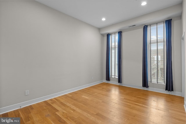 empty room featuring light wood finished floors, baseboards, and recessed lighting