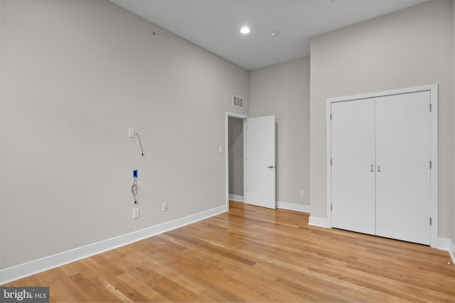 unfurnished bedroom with visible vents, baseboards, light wood-style flooring, a high ceiling, and recessed lighting