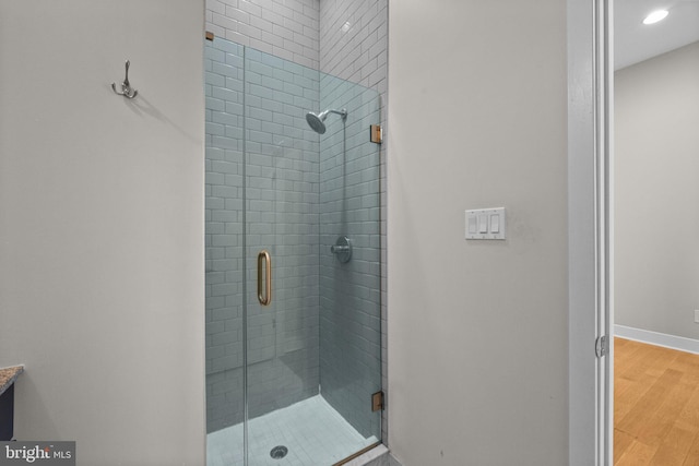 full bathroom with a shower stall, baseboards, wood finished floors, and vanity