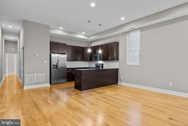 kitchen with stainless steel appliances, visible vents, light wood-style floors, open floor plan, and dark brown cabinetry