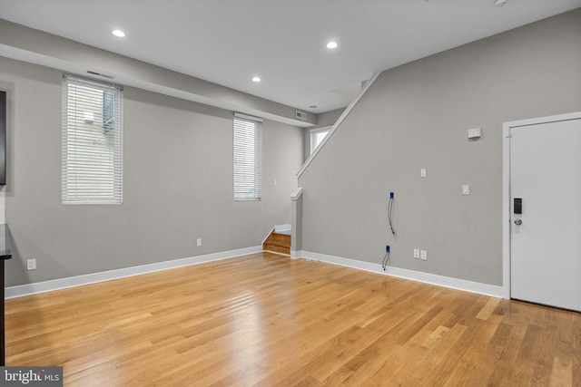 basement featuring stairs, light wood-type flooring, baseboards, and recessed lighting