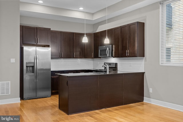 kitchen with stainless steel appliances, visible vents, a sink, dark brown cabinets, and a peninsula