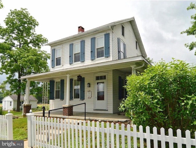 view of front of property with a porch, fence, and a chimney