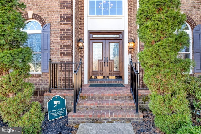 view of exterior entry featuring brick siding and french doors