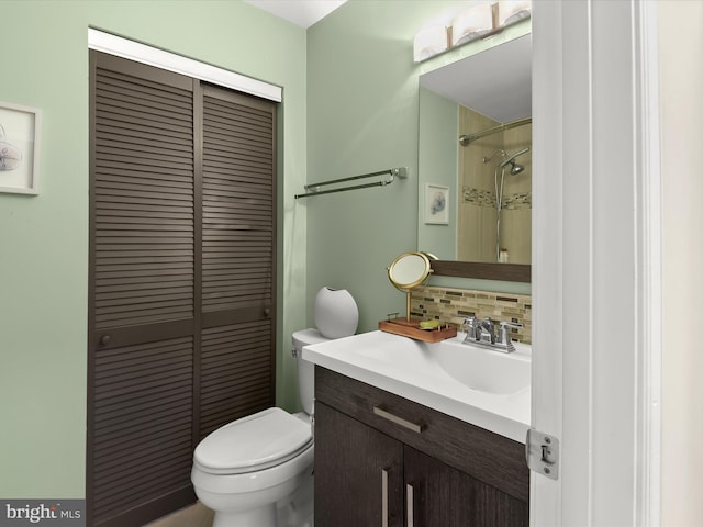 bathroom featuring tasteful backsplash, a shower, toilet, vanity, and a closet