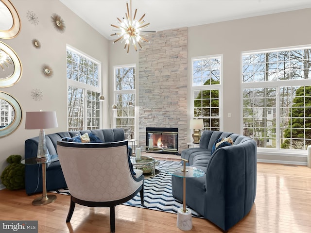 living room with hardwood / wood-style floors, a fireplace, a high ceiling, and a notable chandelier