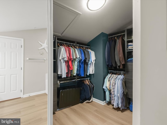 spacious closet featuring attic access, radiator heating unit, and wood finished floors