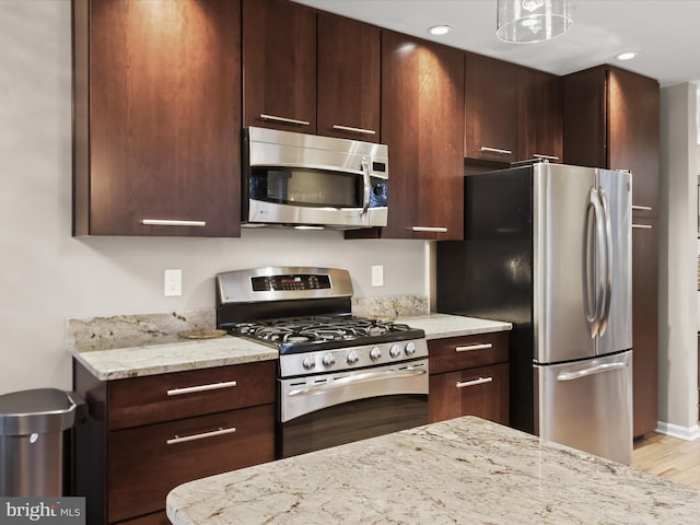 kitchen featuring light stone countertops, appliances with stainless steel finishes, dark brown cabinets, and recessed lighting