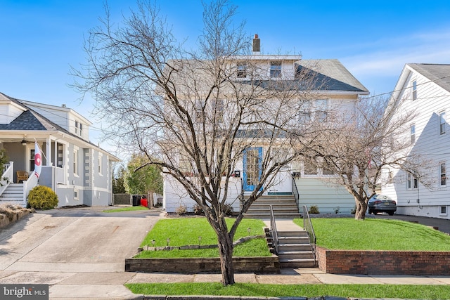 american foursquare style home featuring a front yard, driveway, and a chimney