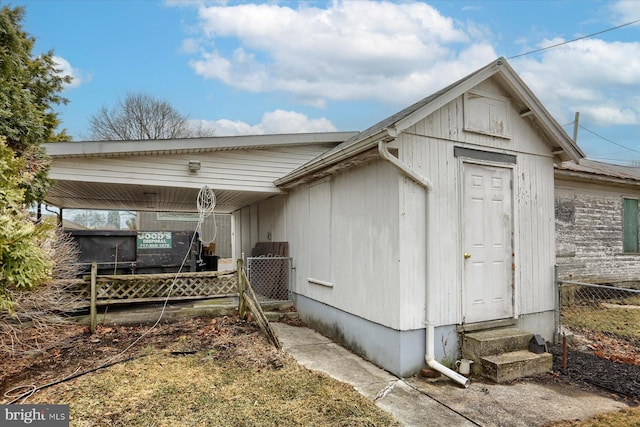 view of property exterior with entry steps, fence, and a carport