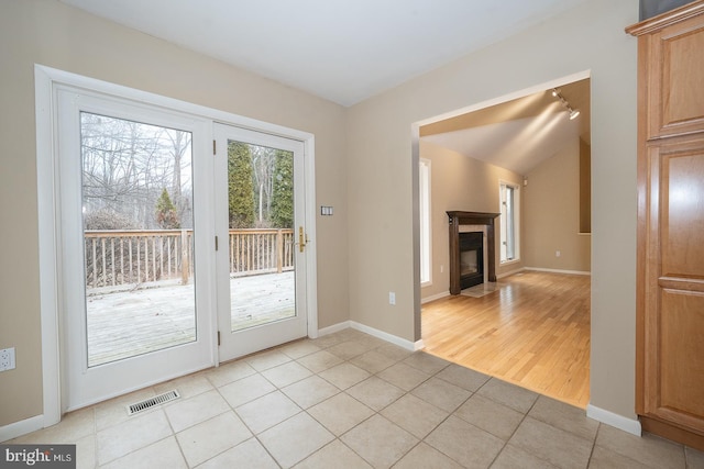 doorway featuring a tile fireplace, visible vents, baseboards, and light tile patterned flooring