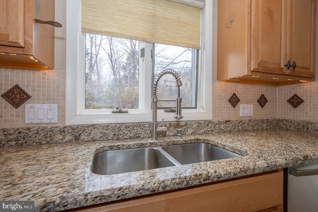 kitchen featuring light stone countertops, backsplash, and a sink