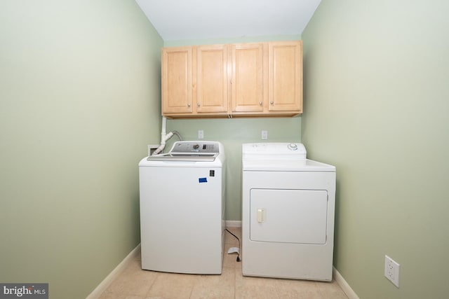 clothes washing area featuring cabinet space, washing machine and dryer, light tile patterned floors, and baseboards