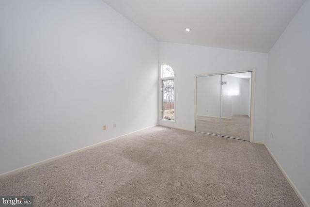 unfurnished bedroom featuring high vaulted ceiling, carpet, baseboards, and a closet