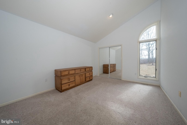 unfurnished bedroom featuring carpet floors, high vaulted ceiling, and baseboards