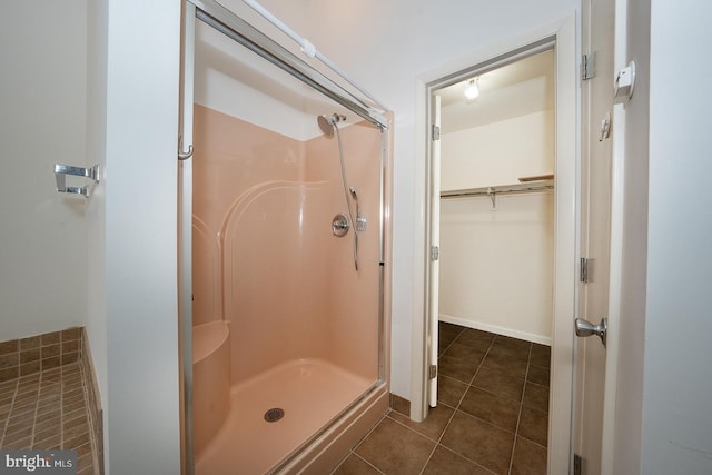 bathroom with a stall shower, tile patterned flooring, baseboards, and a walk in closet