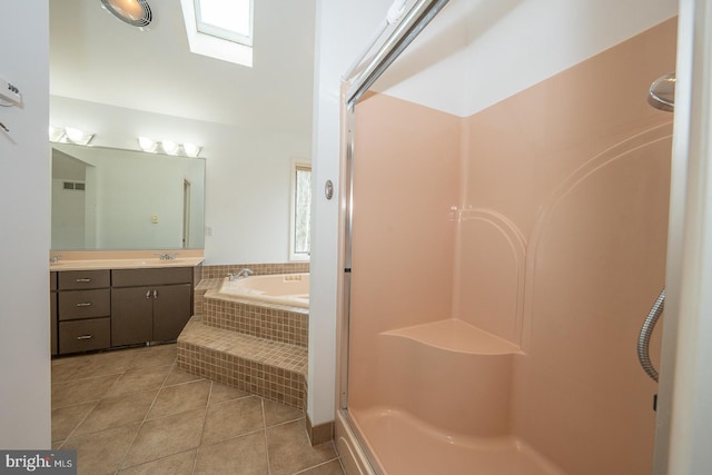 bathroom with a skylight, a garden tub, tile patterned flooring, walk in shower, and vanity