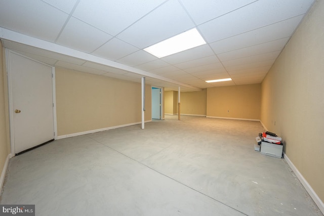 finished below grade area featuring a drop ceiling and baseboards