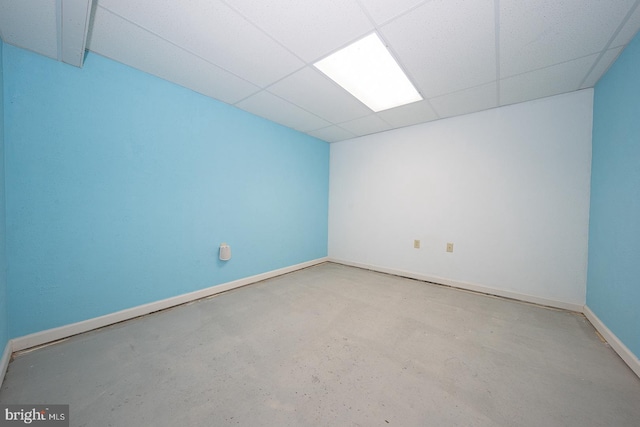 spare room featuring concrete floors, baseboards, and a drop ceiling