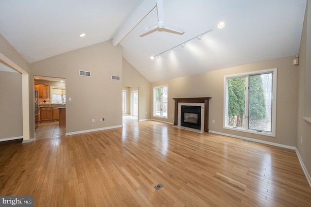 unfurnished living room with light wood finished floors, a fireplace with flush hearth, visible vents, and a ceiling fan