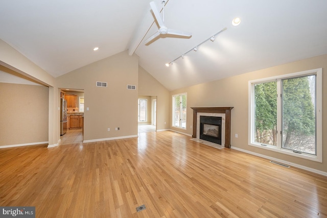 unfurnished living room with plenty of natural light, light wood finished floors, a fireplace with flush hearth, and visible vents