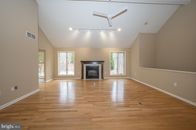 unfurnished living room with light wood-type flooring, a fireplace with flush hearth, visible vents, and a healthy amount of sunlight