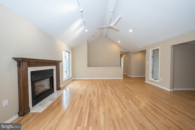 unfurnished living room with baseboards, a tiled fireplace, ceiling fan, light wood-type flooring, and beam ceiling