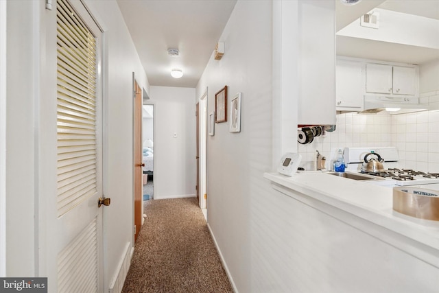 hall featuring carpet, visible vents, and baseboards