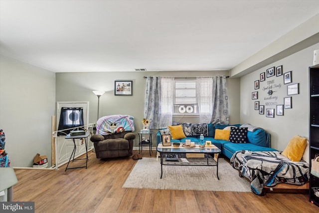 living area with baseboards, visible vents, and wood finished floors