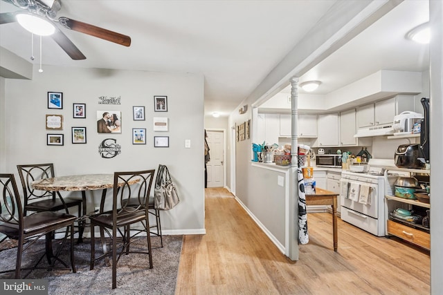 kitchen featuring gas range gas stove, light countertops, stainless steel microwave, light wood-type flooring, and under cabinet range hood