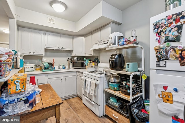 kitchen featuring light wood-style flooring, under cabinet range hood, white appliances, visible vents, and light countertops