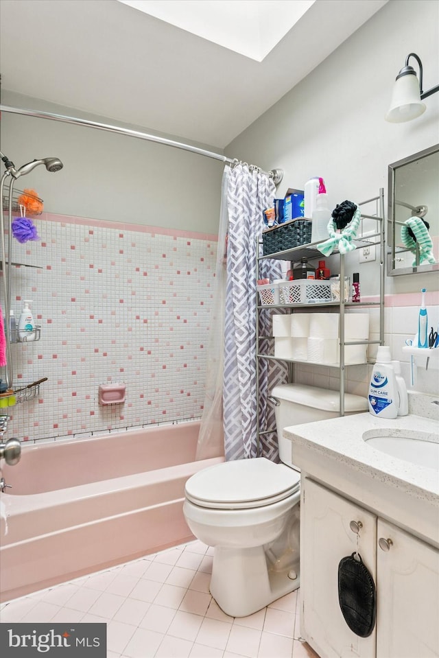 full bathroom featuring a skylight, toilet, tile patterned floors, shower / bath combo with shower curtain, and vanity