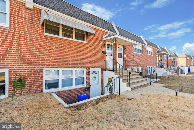 view of front facade featuring a shingled roof, a residential view, brick siding, and mansard roof