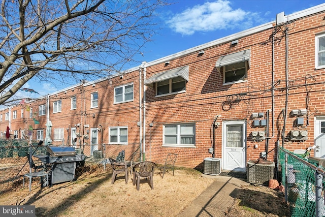 back of house featuring fence, central AC, and brick siding