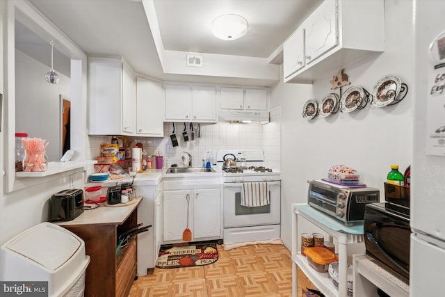 kitchen with white gas stove, light countertops, visible vents, white cabinetry, and a sink