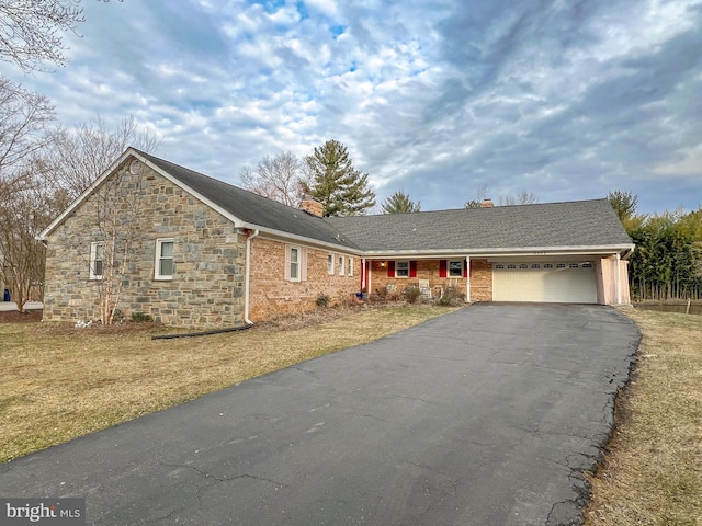 ranch-style house featuring a chimney, driveway, and an attached garage